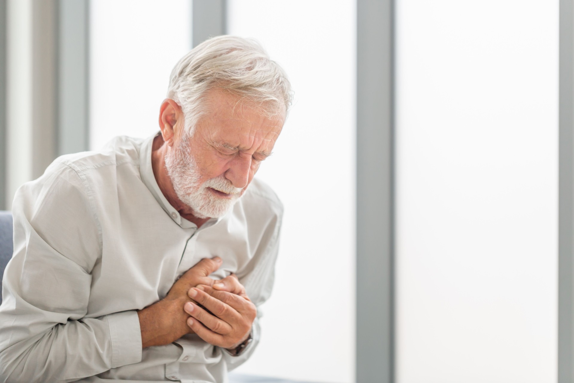 Senior man presses hand to chest has heart attack suffers from unbearable pain, Mature man with pain on heart in living room